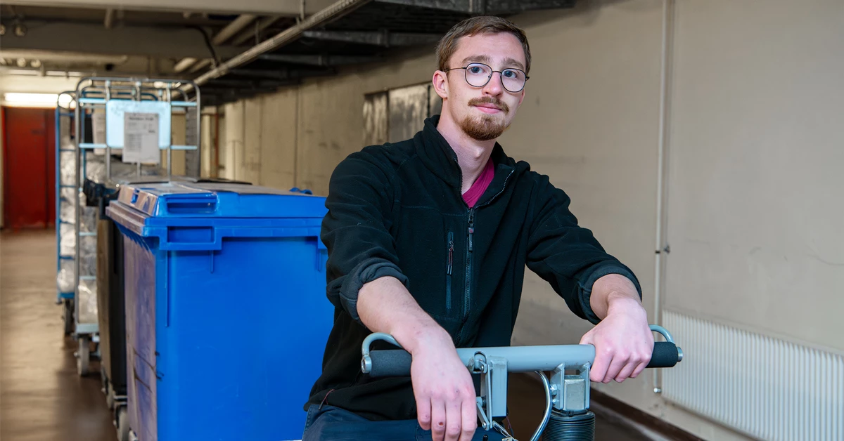 CSR-jobber Mads Jørgensen transportere en blå affaldscontainer.